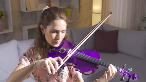 Talented-musician-woman-playing-violin-in-living-room-at-home.